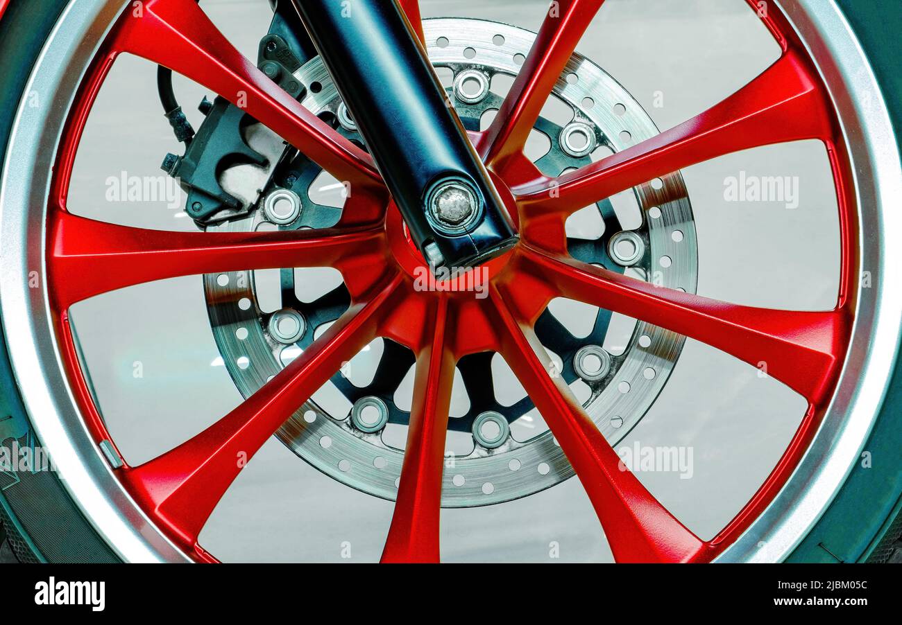 Wheel of modern motorcycle. Spokes, brake disc, pads. Close-up. Red, black, chrome color Stock Photo