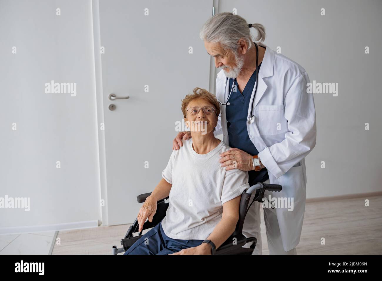 Professional male doctor carrying female patient on wheelchair in