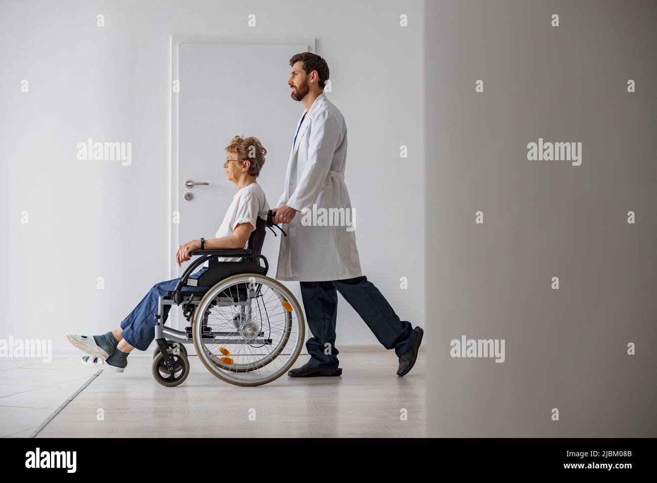 Professional male doctor carrying female patient on wheelchair in