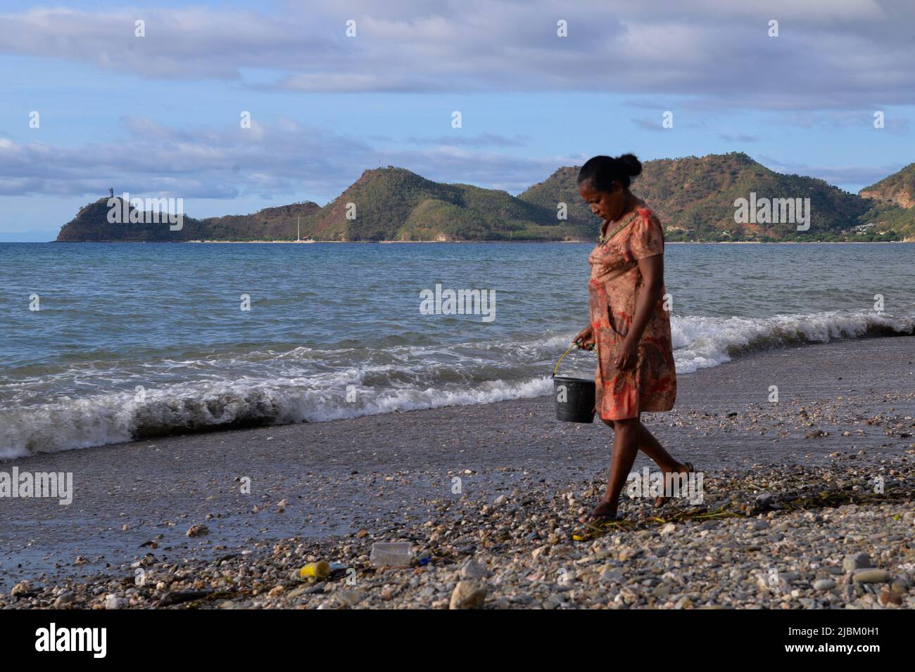 Dili, Timor-Leste. 6th June, 2022. A woman collects stones on a beach