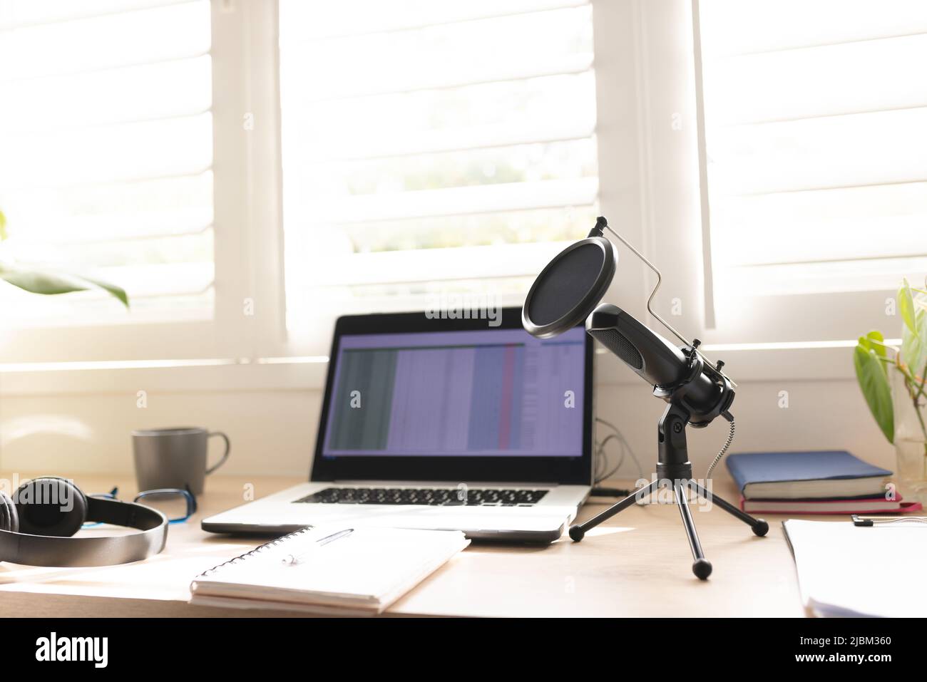 Condenser microphone with laptop on table by window at home studio Stock Photo