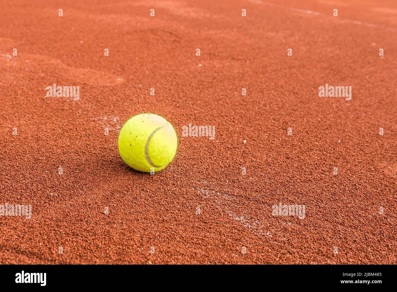 Clay red court with a yellow tennis ball Stock Photo