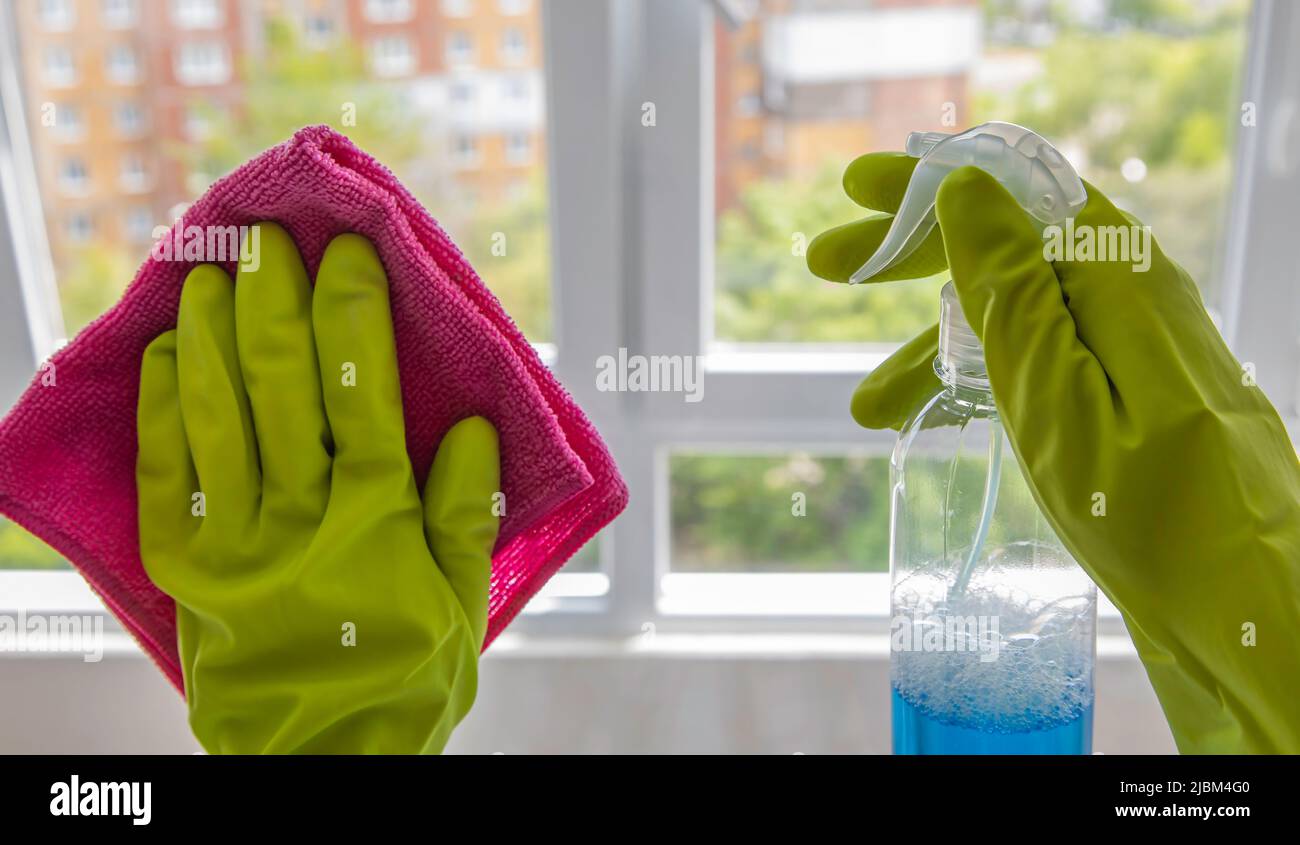 Close up of green rubber gloves, rag and window cleaner. Stock Photo