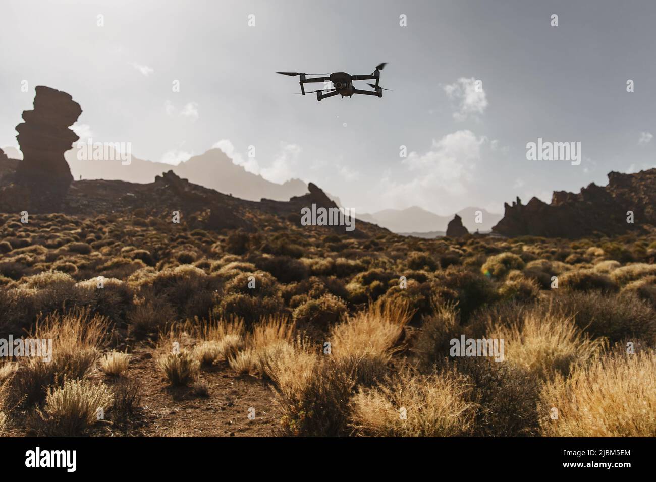 Folding small drone is flying over the mountains. Stock Photo