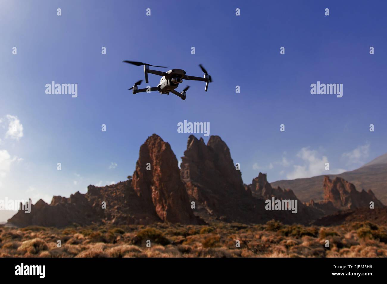 Folding small drone is flying over the mountains. Stock Photo