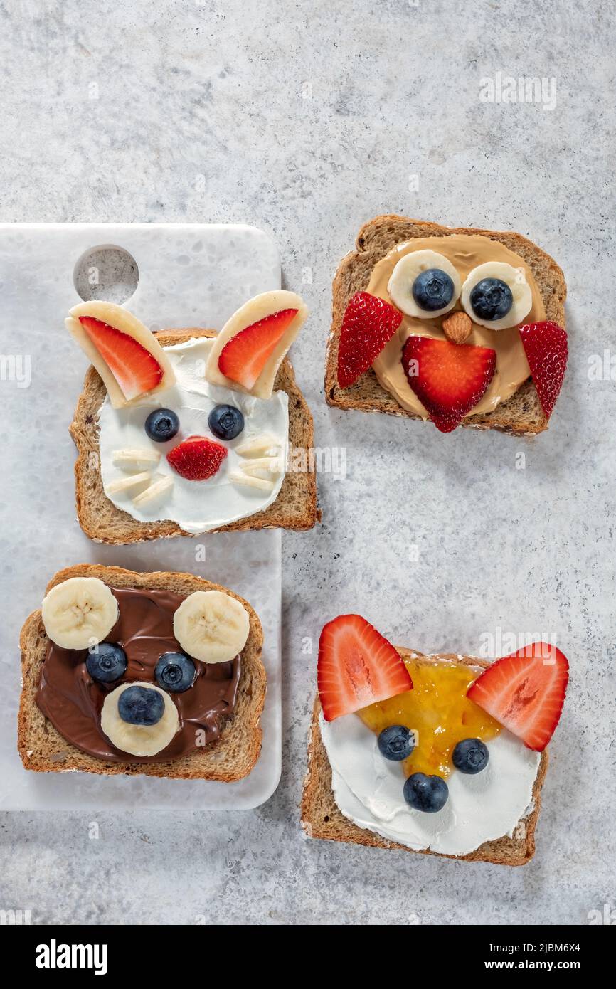 Funny animal faces toasts with spreads, butters, banana, strawberry and blueberry. Look like bunny, owl, bear, fox Stock Photo