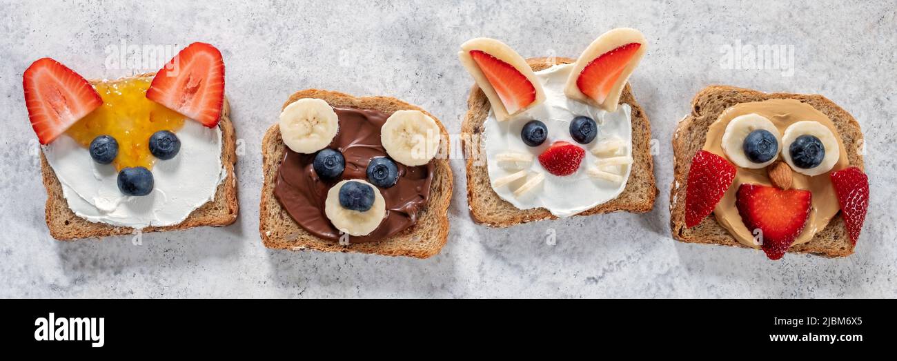 Funny animal faces toasts with spreads, butters, banana, strawberry and blueberry. Look like bunny, owl, bear, fox Stock Photo