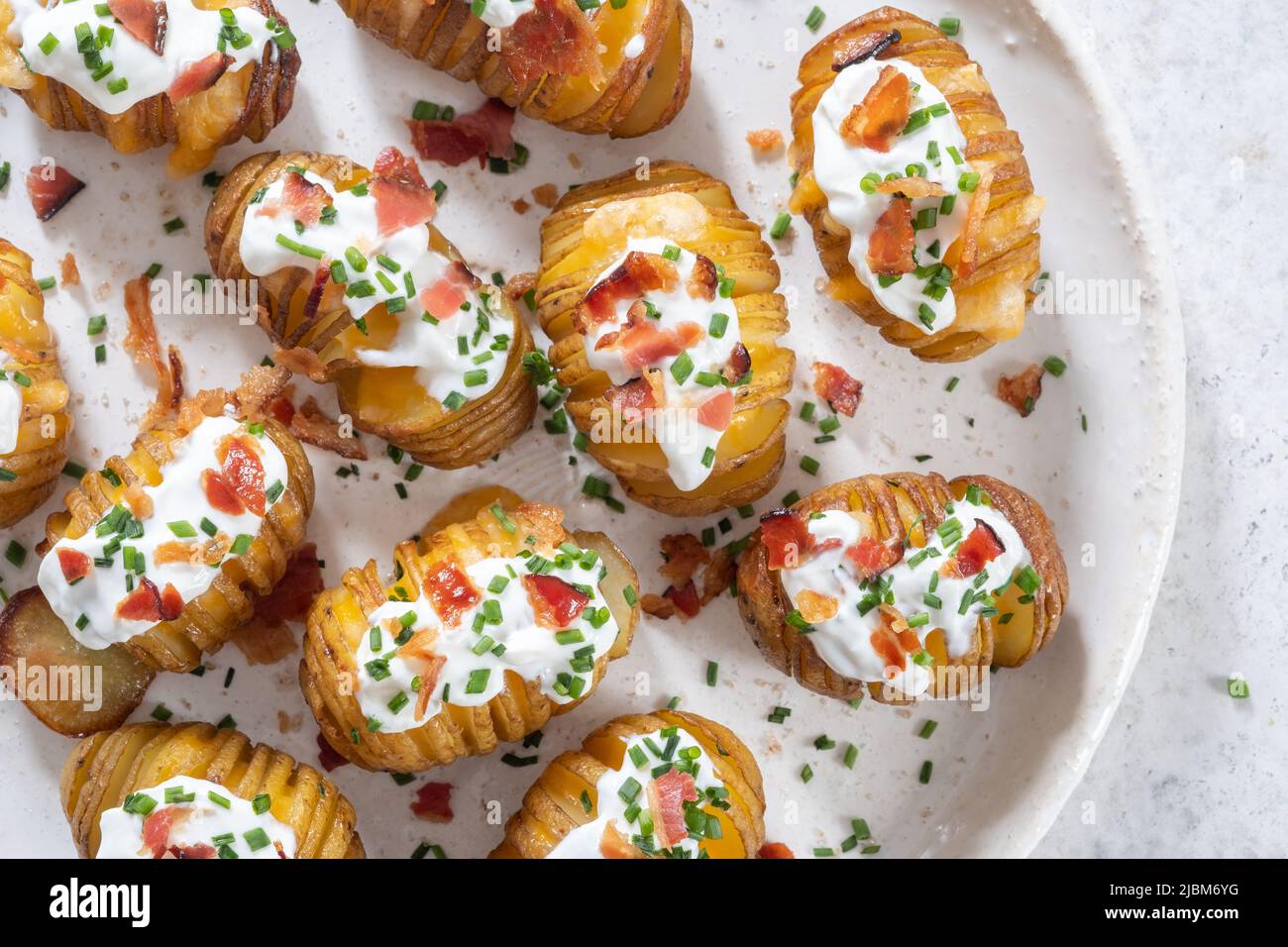 baked potato stuffed with cheese, bacon and sour cream. loaded hasselback potatoes Stock Photo