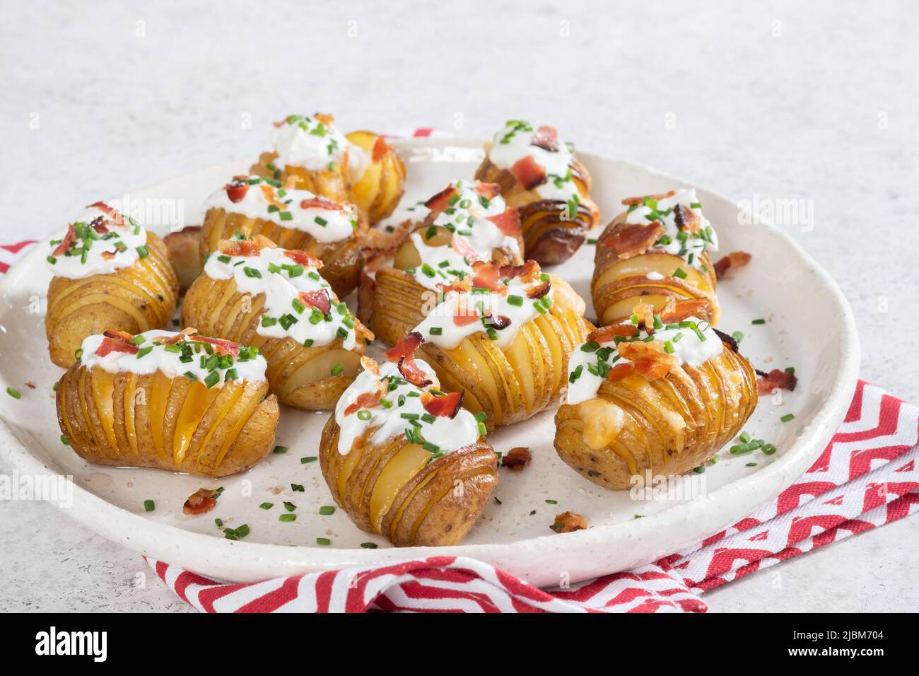 baked potato stuffed with cheese, bacon and sour cream. loaded hasselback potatoes Stock Photo