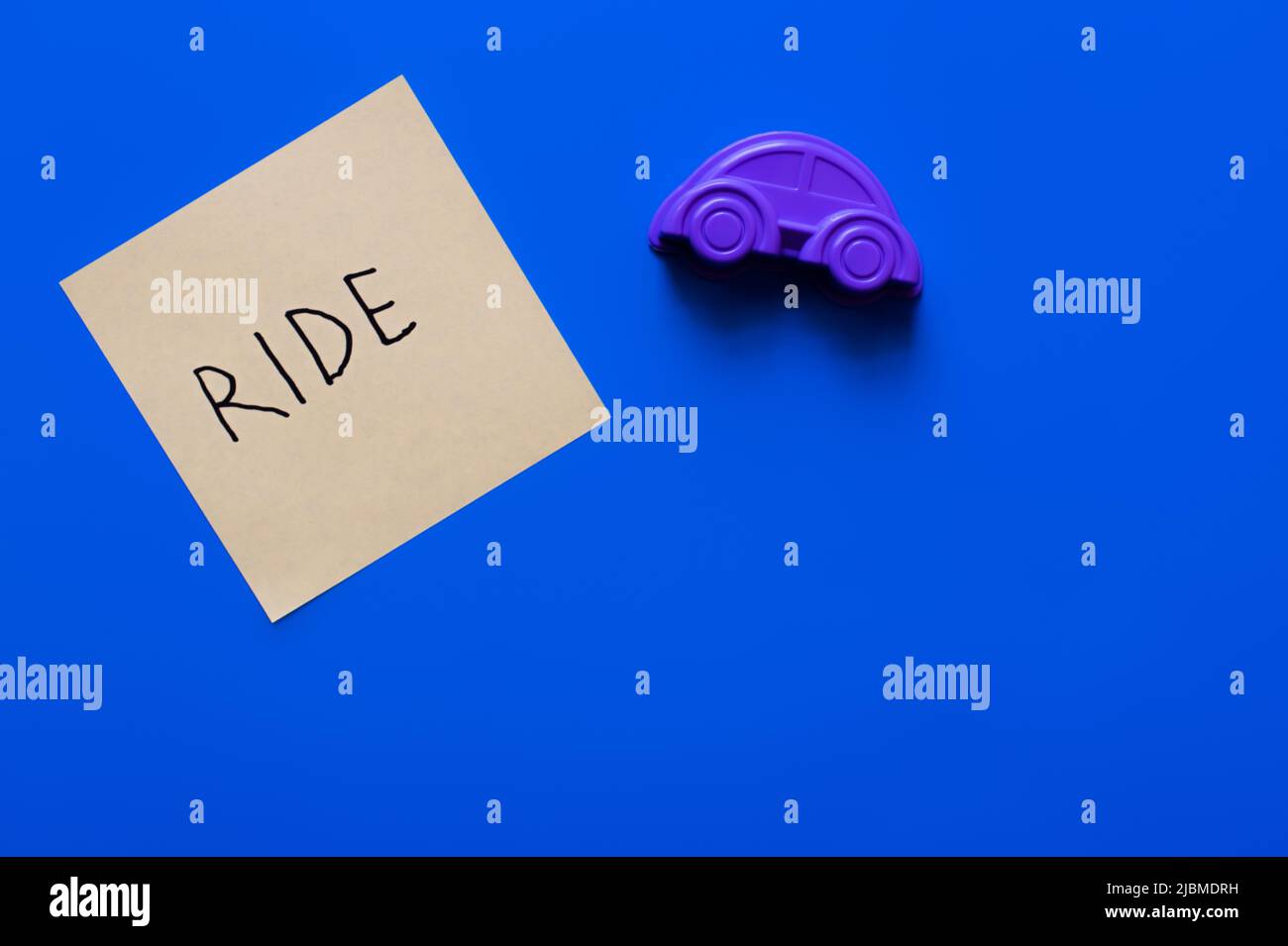 top view of paper with ride inscription near purple toy car on blue ...