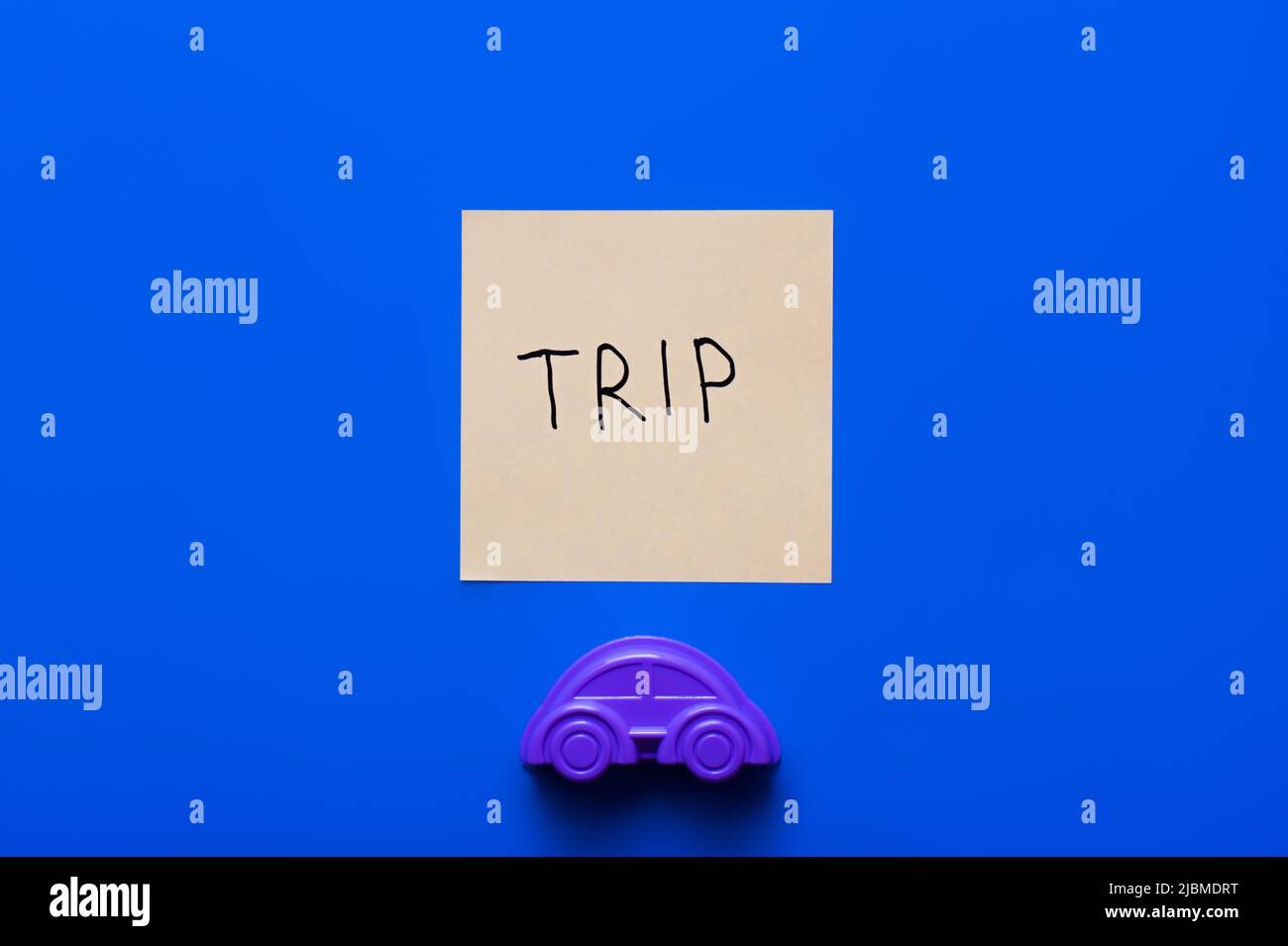 top view of paper card with trip lettering near purple toy car on blue