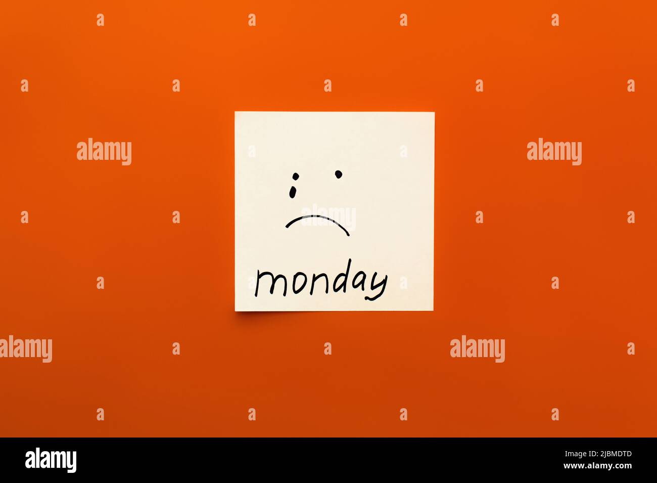 top view of paper note with crying emoticon and monday lettering on orange background Stock Photo