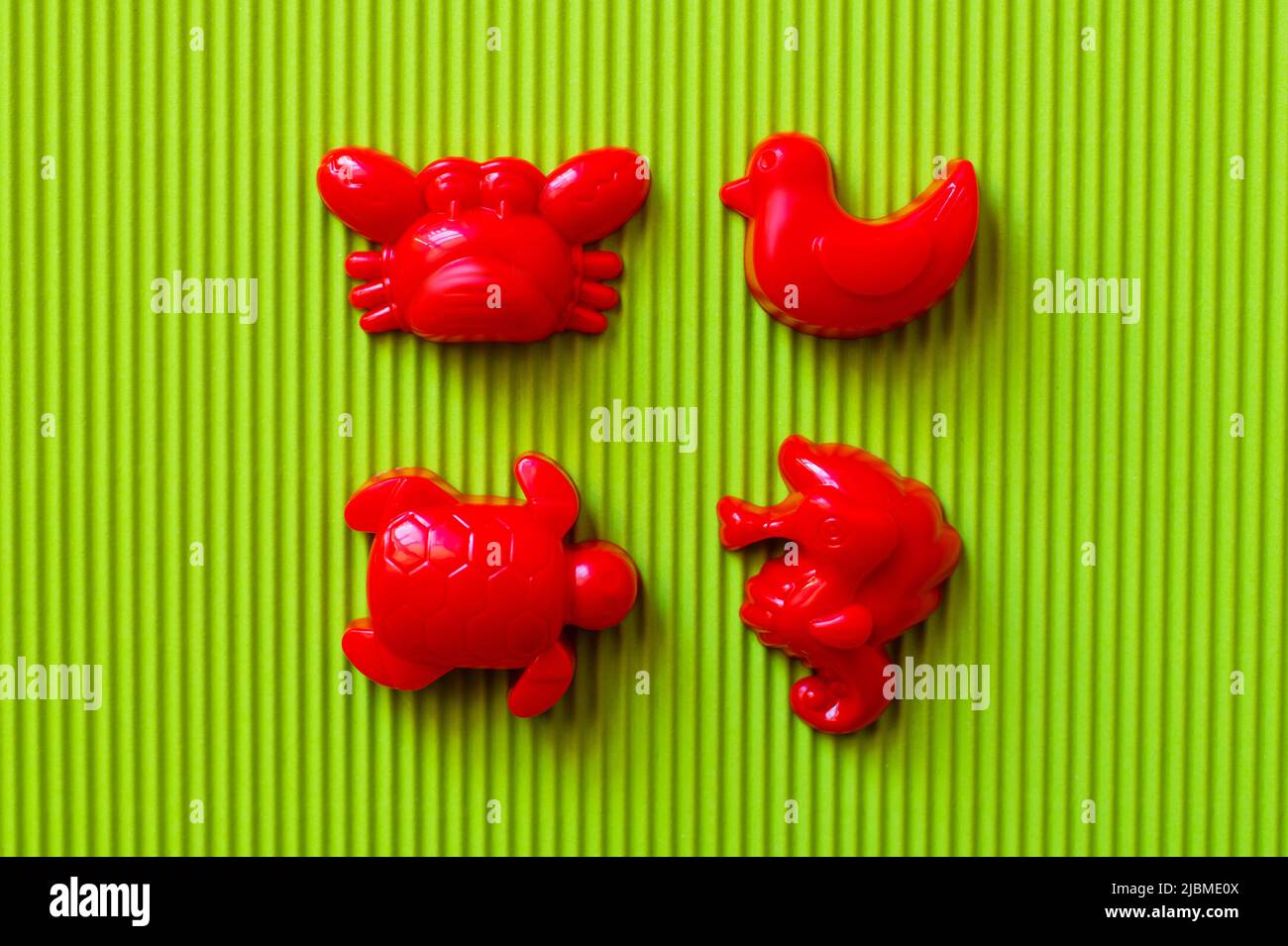 top view of red sea animals and duck toys on green corrugated background Stock Photo