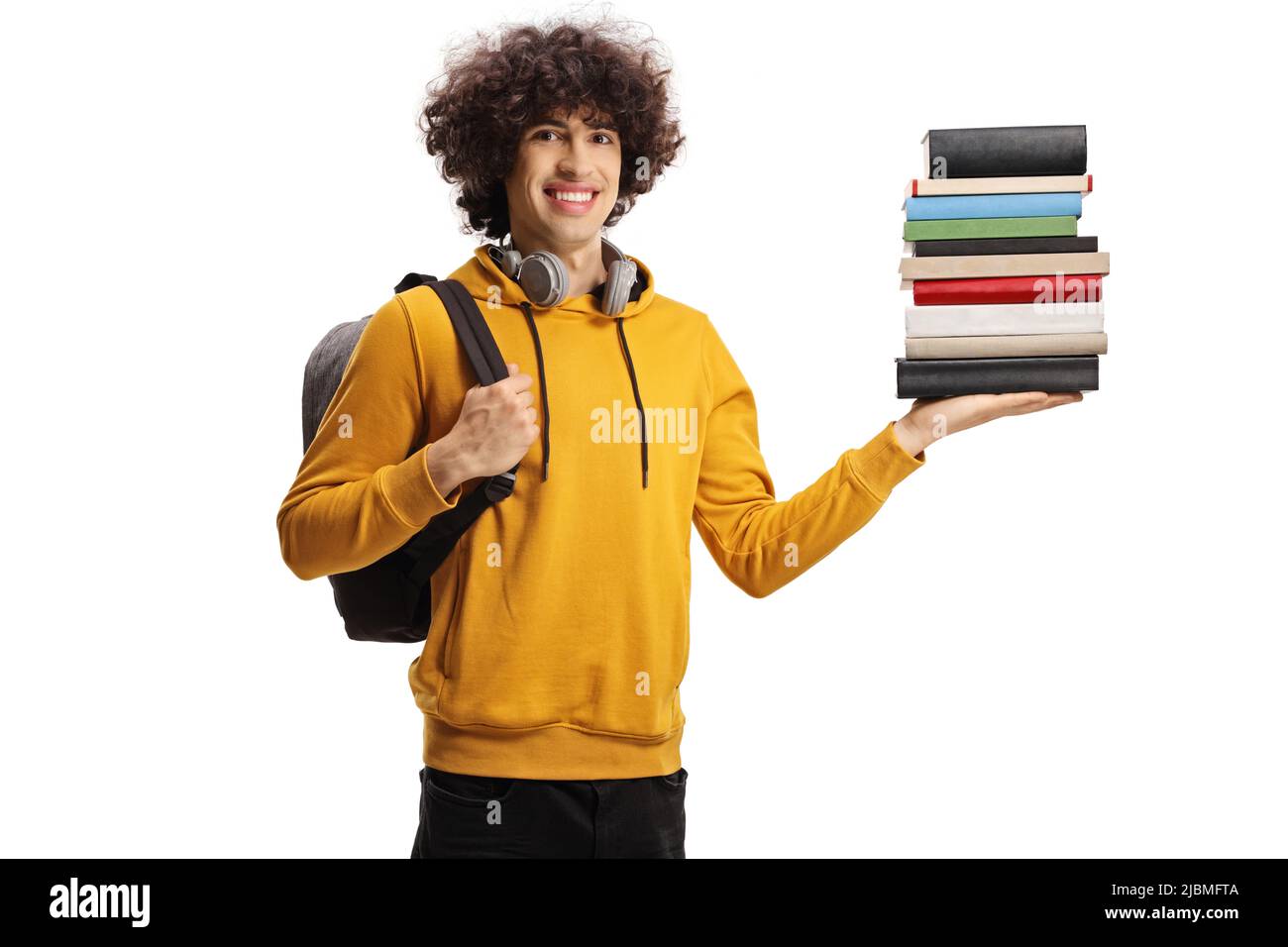 Cheerful male student holding a pile of books and carrying a backpack ...
