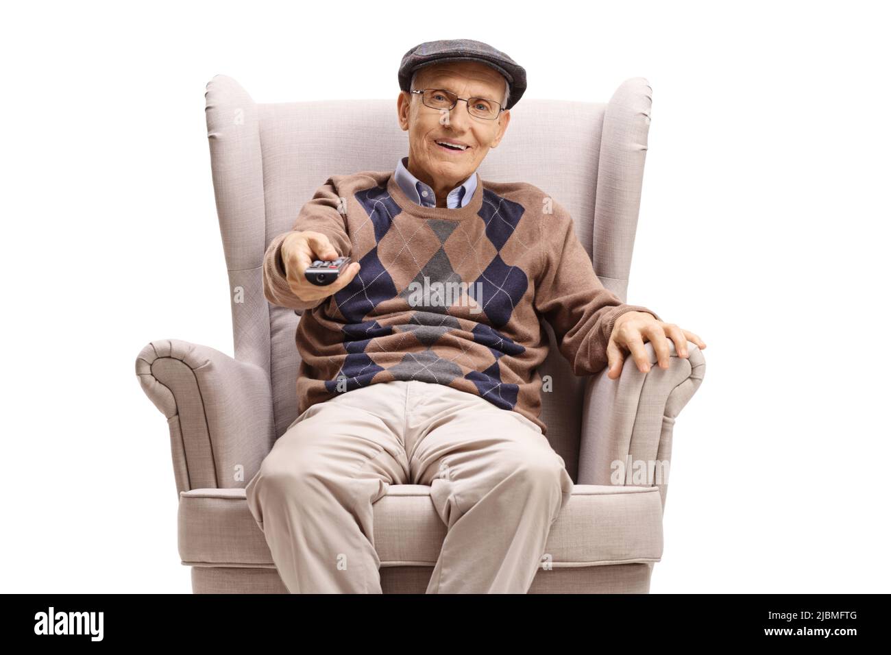 Pensioner sitting in an armchair and using a tv remote control isolated on white background Stock Photo