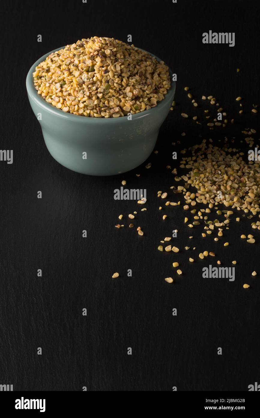 split skin removed mung beans or green grams in ceramic bowl on black surface, also known as moong seeds, staple ingredient in southeast asian dishes Stock Photo