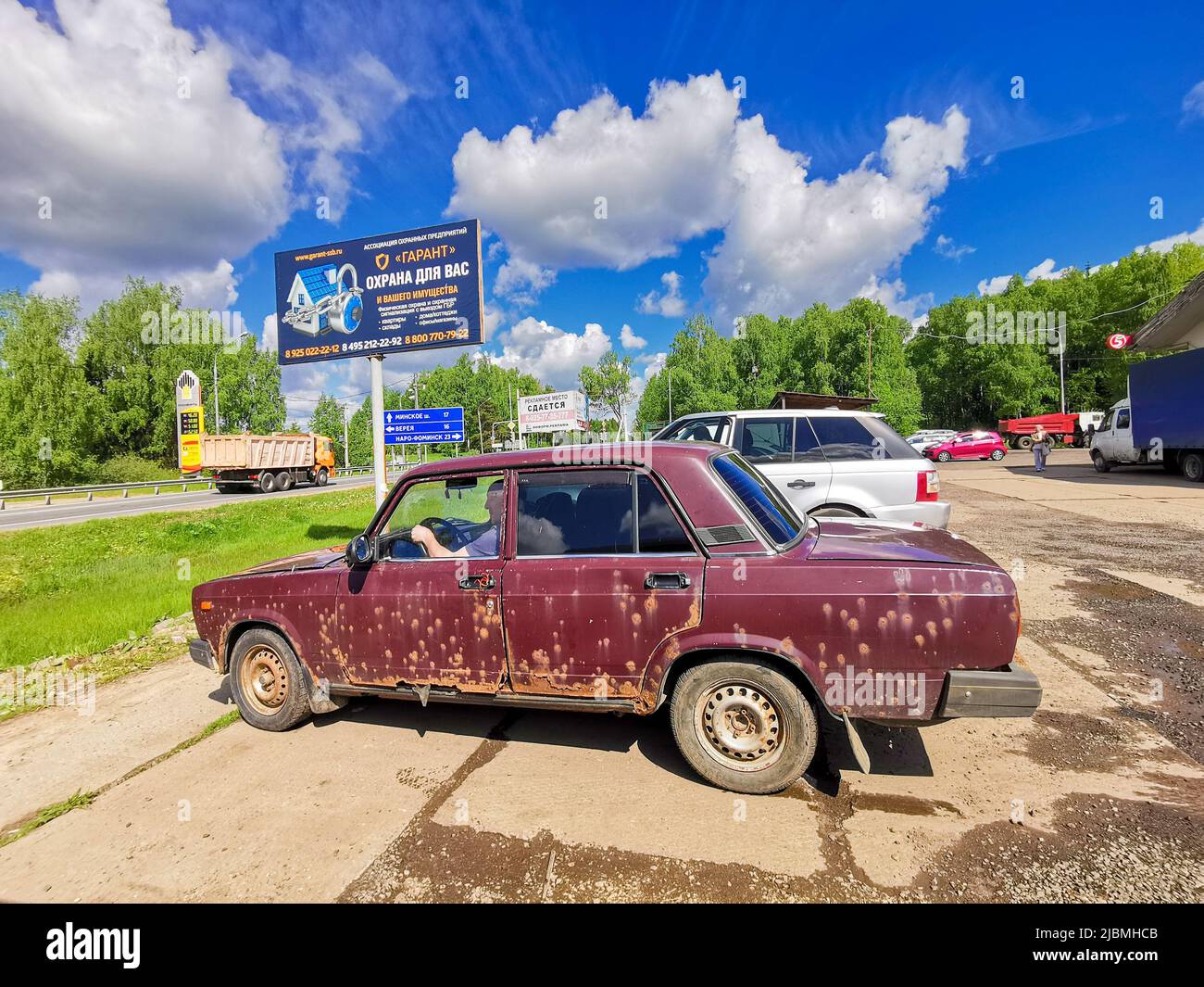 Moscow region. Russia. June 4, 2022. Old Soviet car VAZ 2107 on a sunny day. Burgundy retro car Zhiguli with numerous pockets of rust on the body. Stock Photo
