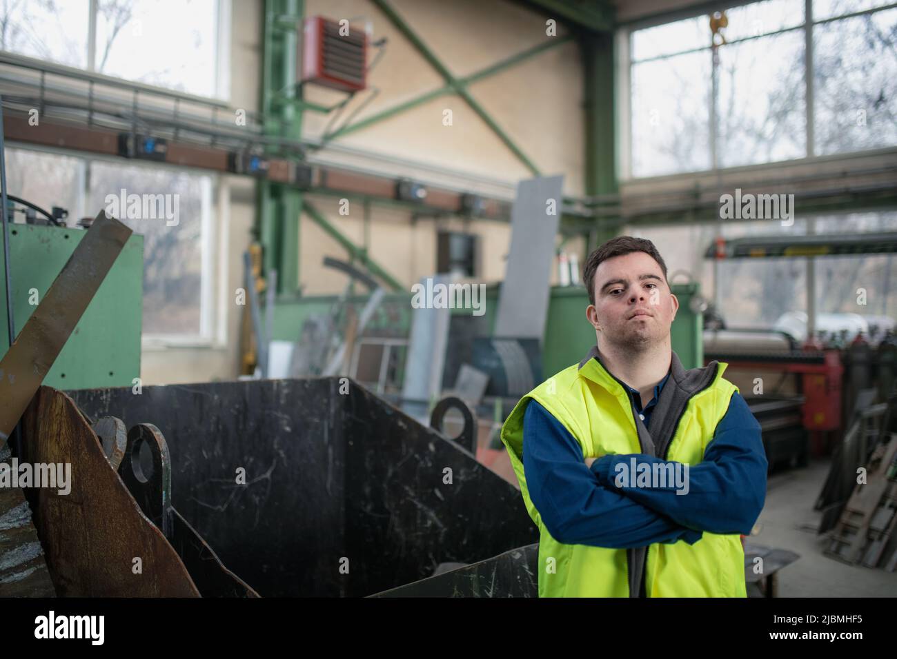 Young man with Down syndrome working in industrial factory, social integration concept. Stock Photo