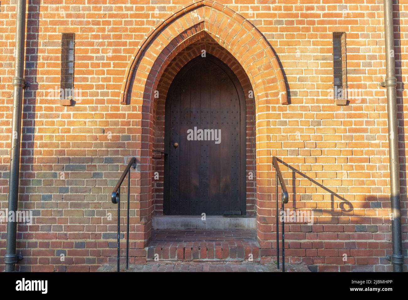 Church doorway, metal railings and red bricks. Stock Photo