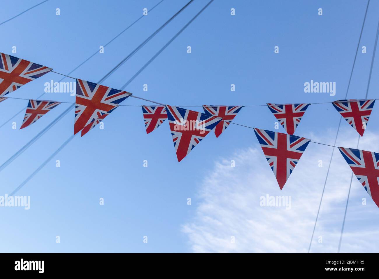 Union Jack bunting, in blue sky with telephone cables. Stock Photo