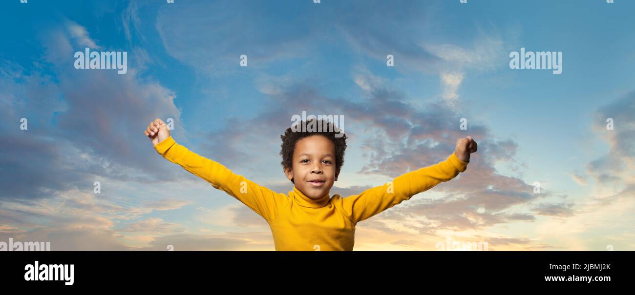 Black kid boy having fun against blue sky clouds background Stock Photo