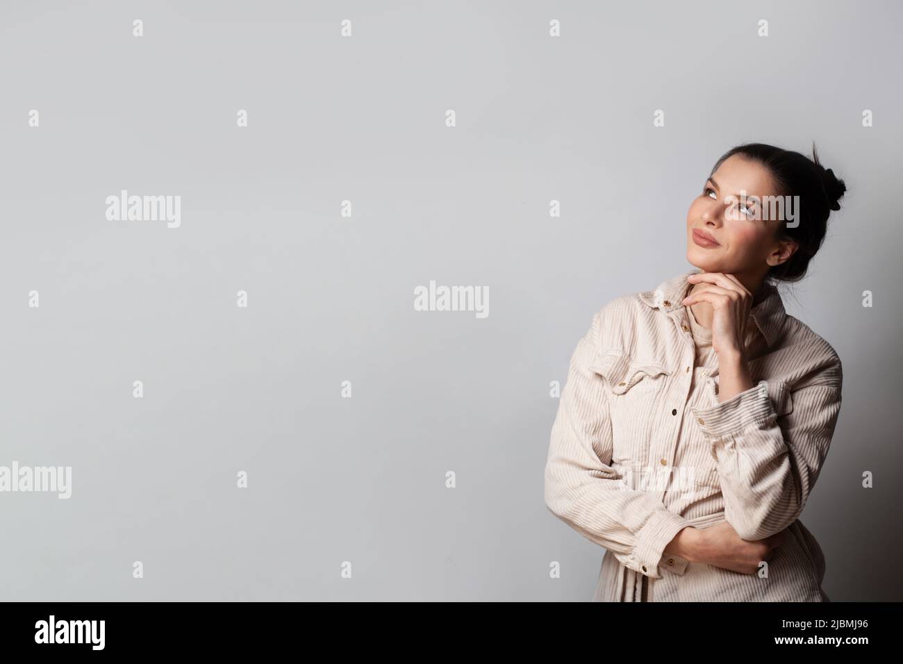 Smiling young woman looking up on grey banner background Stock Photo