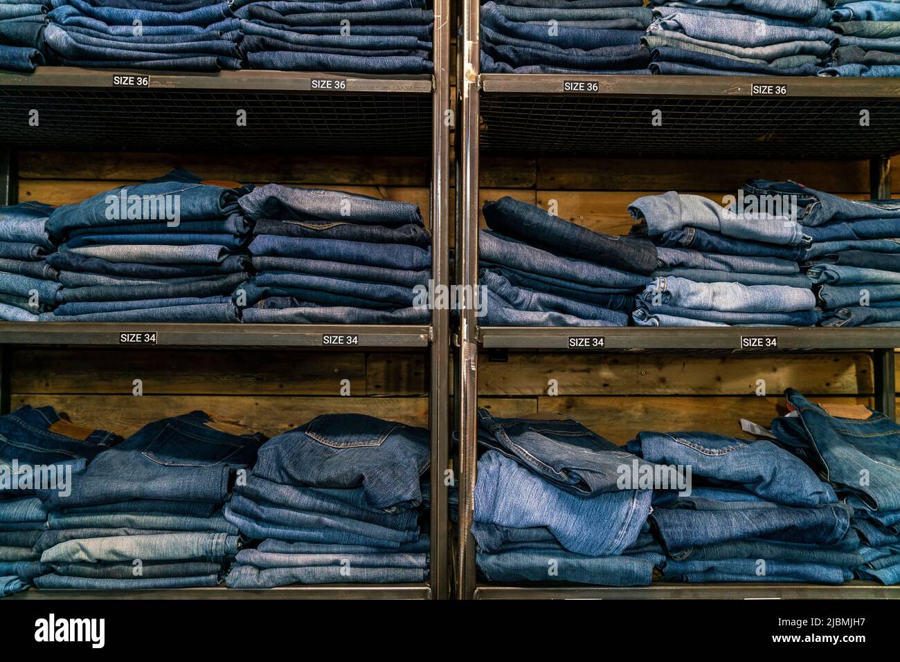 Different sizes of blue denim jeans on display in a high street clothes shop or store Stock Photo