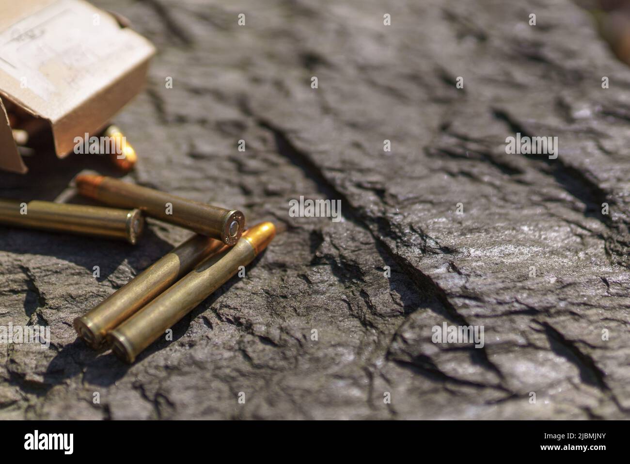 Rifle bullets and cartridges close-up on rock outdoors. Stock Photo
