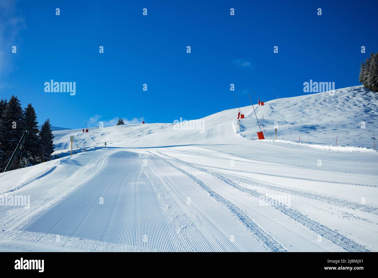Fresh alpine ski track without people in the sunny morning Stock Photo