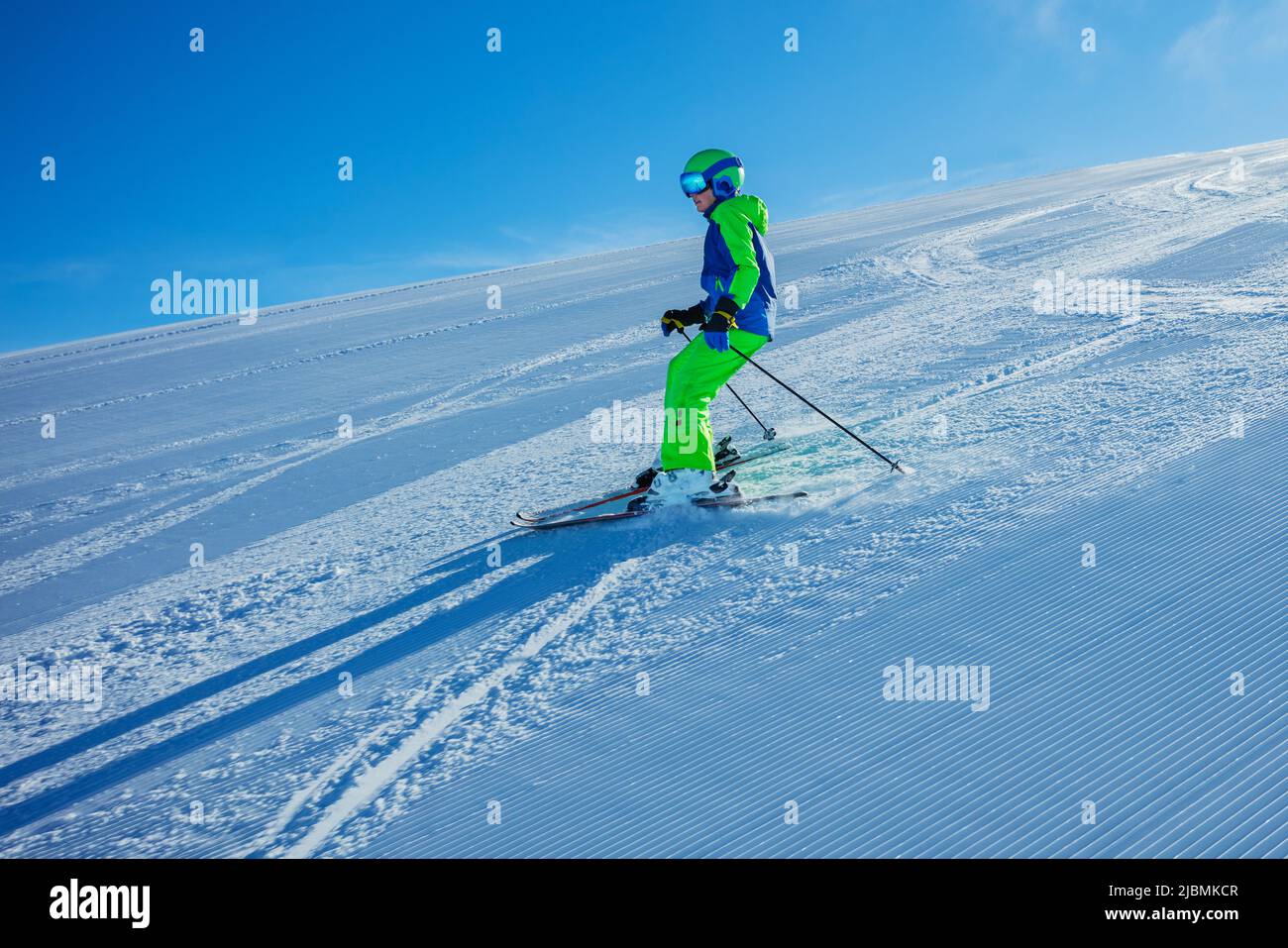 Boy ski downhill fast on the fresh track, sunny morning Stock Photo