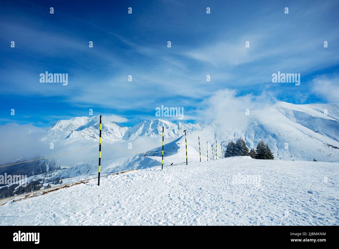 Ski track start on top of a mountain over summits in clouds Stock Photo