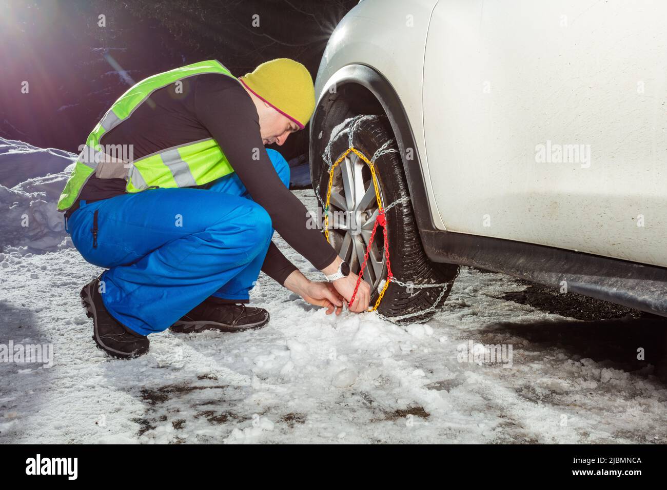 Man put on winter chains for car wheel at snowy road Stock Photo