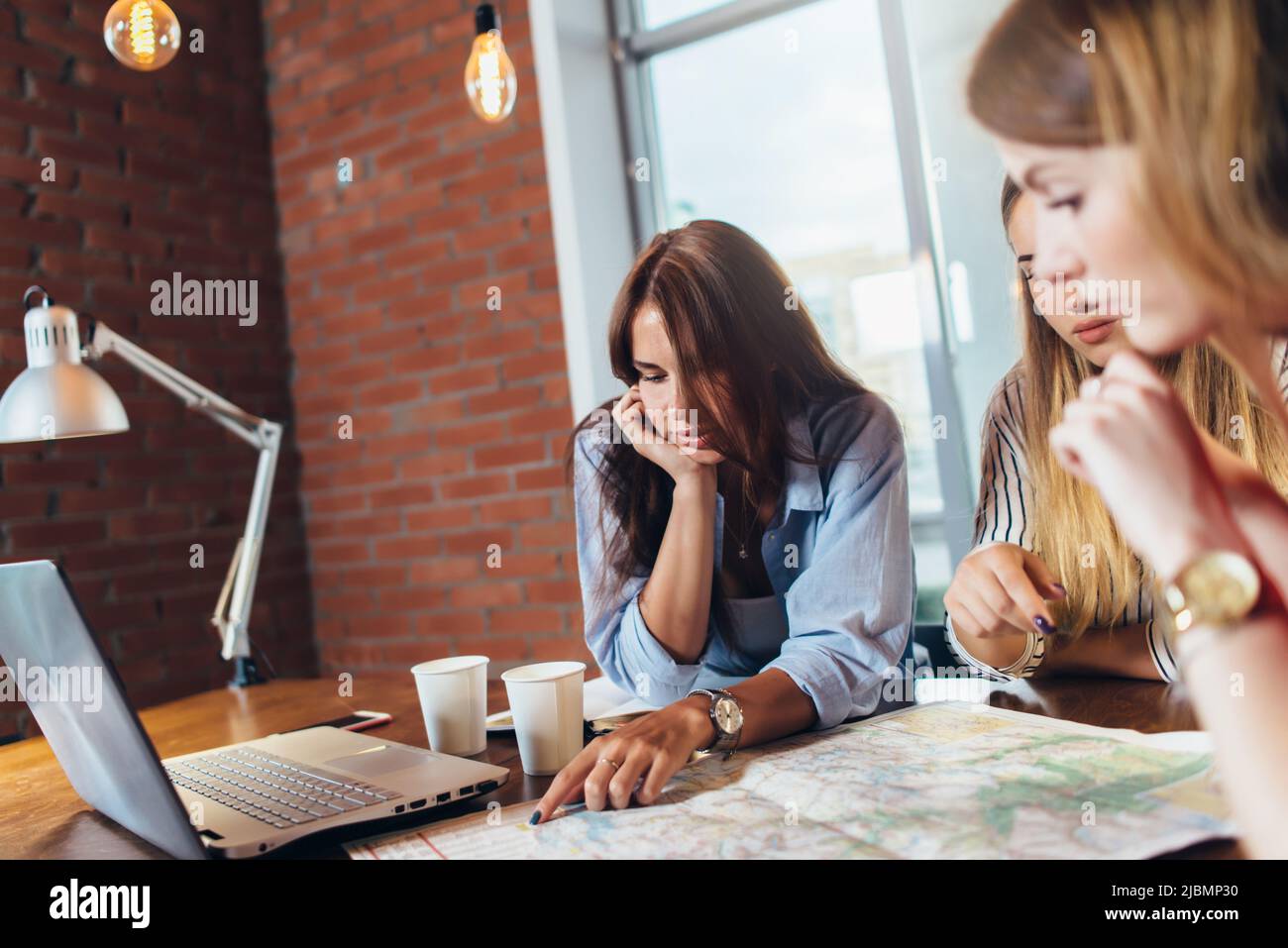 Female office workers planning vacation using map. Stock Photo