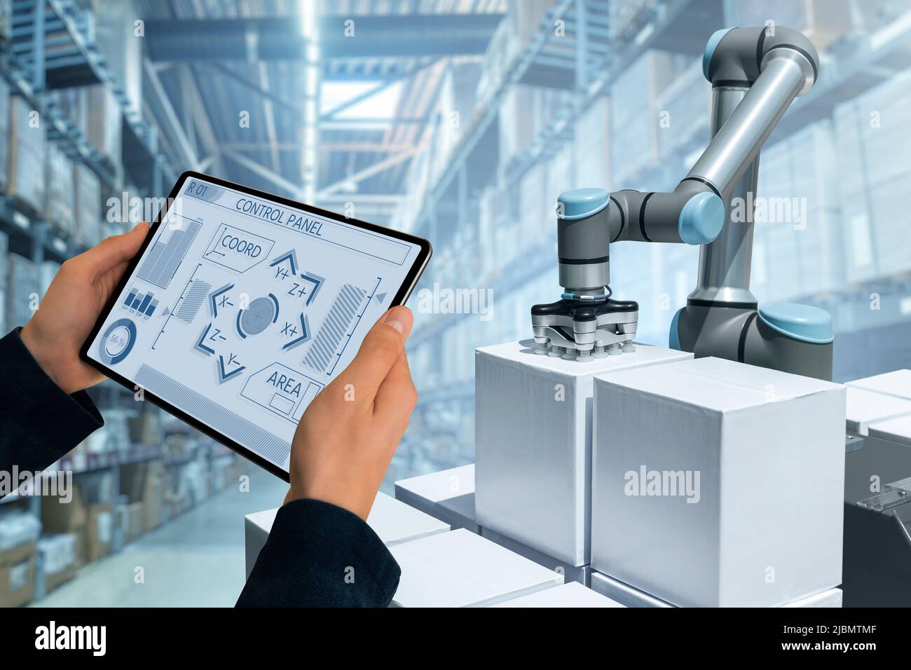 Warehouse manager with digital tablet controls robot arm Stock Photo