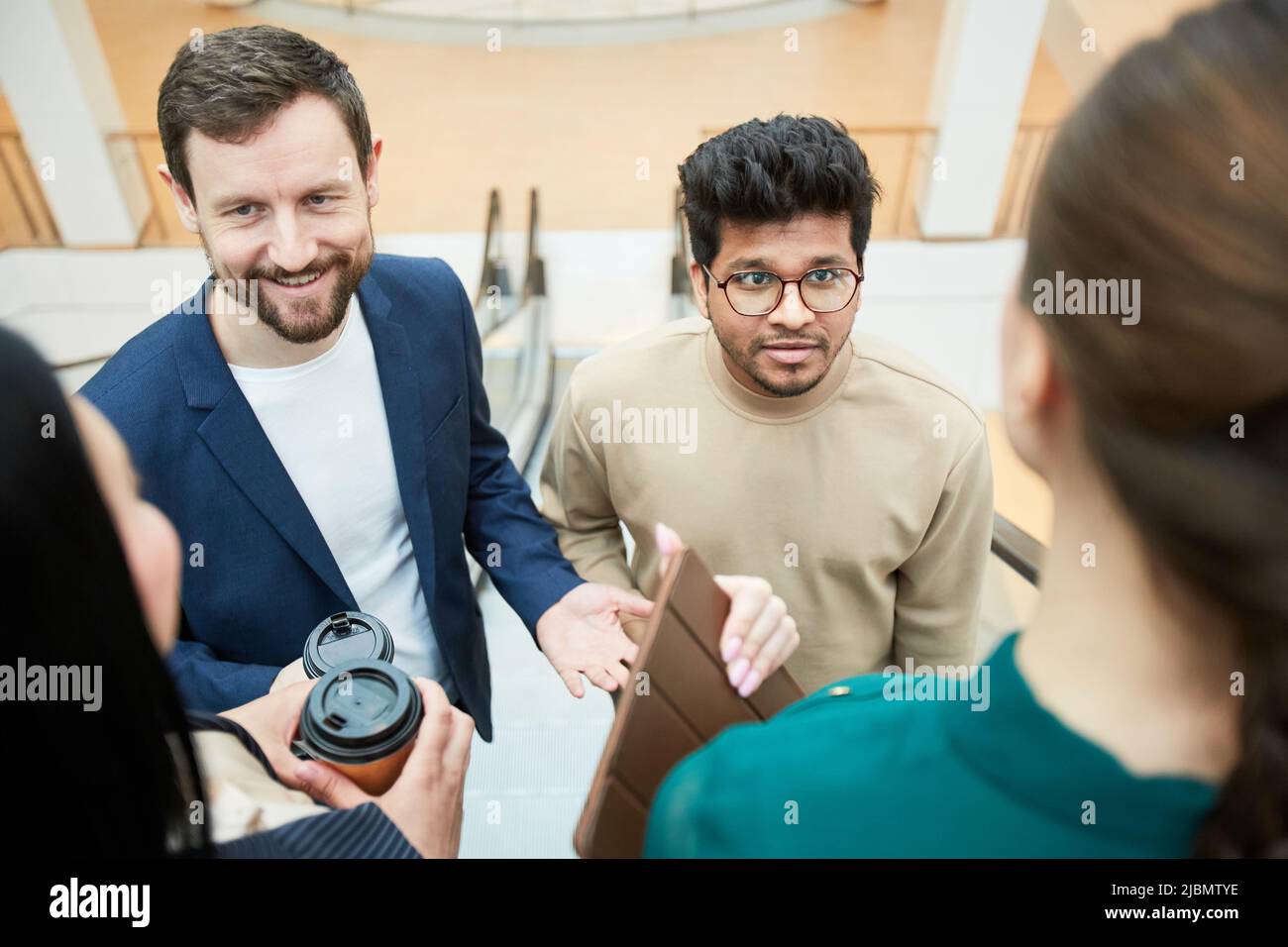 High angle view at diverse business team communicating while standing on escalator Stock Photo