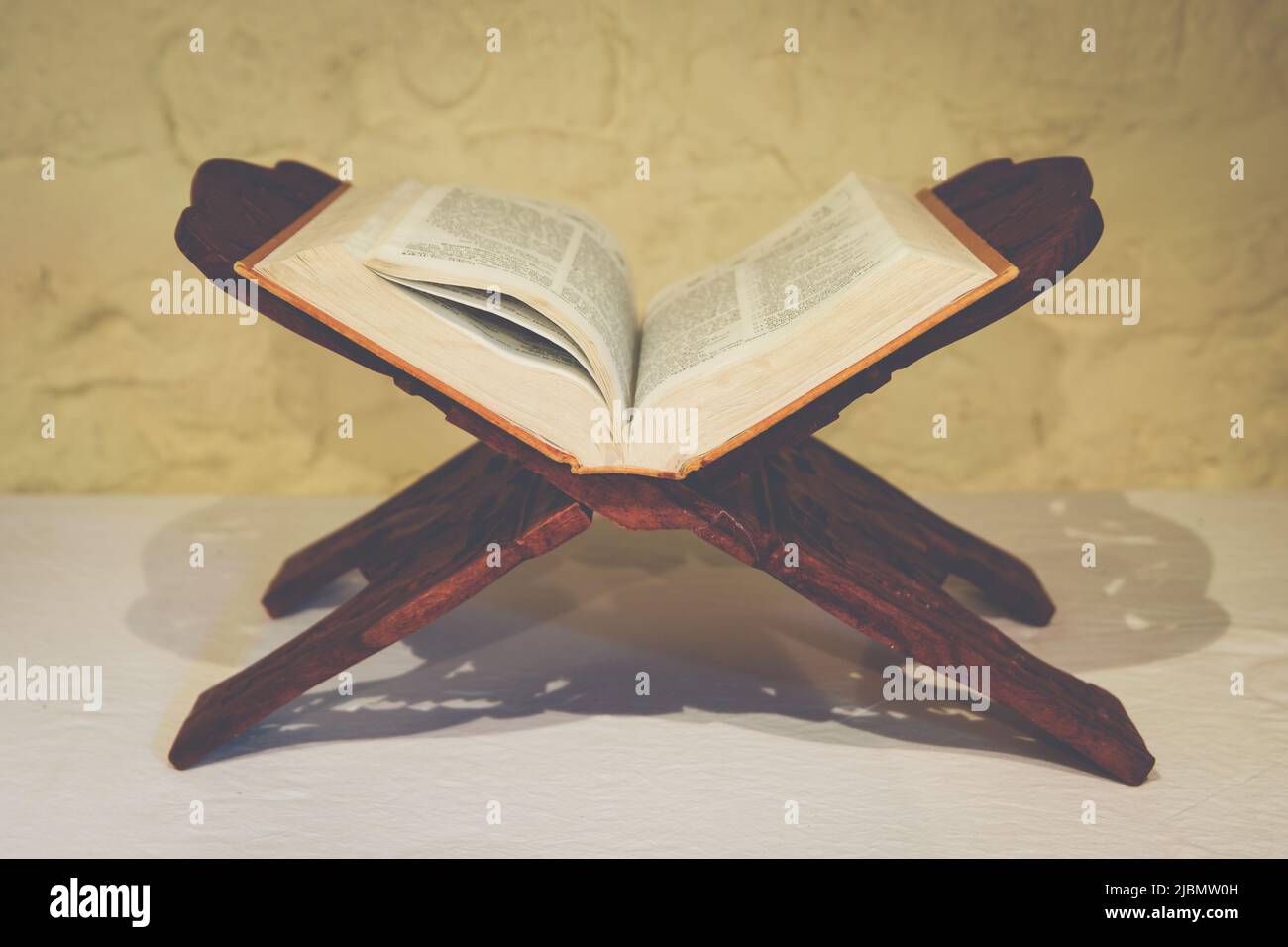 Open Holy Bible on ornate wooden book stand in ascetic setting for meditation and contemplation Stock Photo