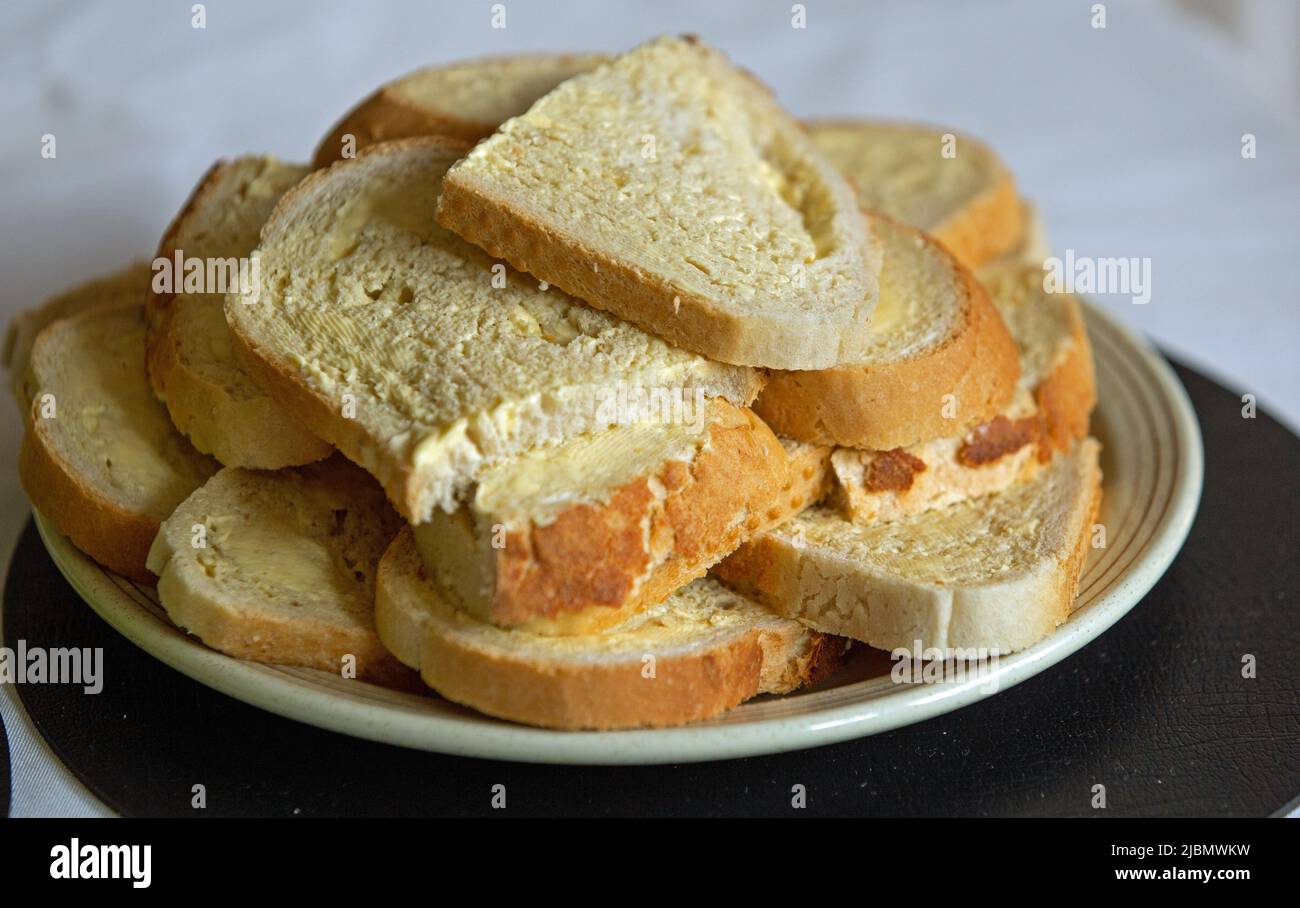 Slices of buttered white bread piled on a plate and shot close up in landscape format Stock Photo
