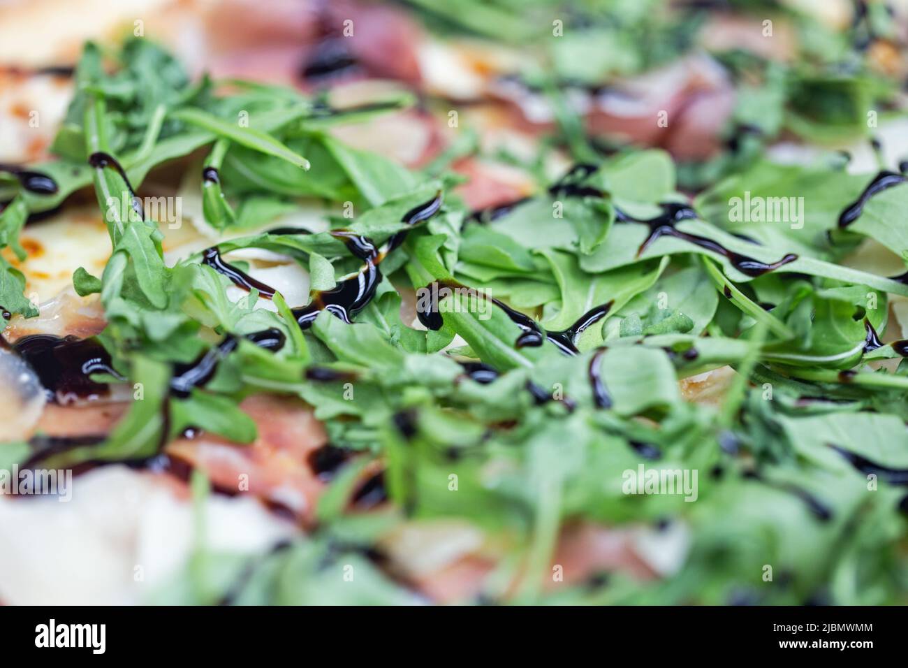 Pizza with rocket and balsamic vinegar and ham shot close up for use as a background Stock Photo