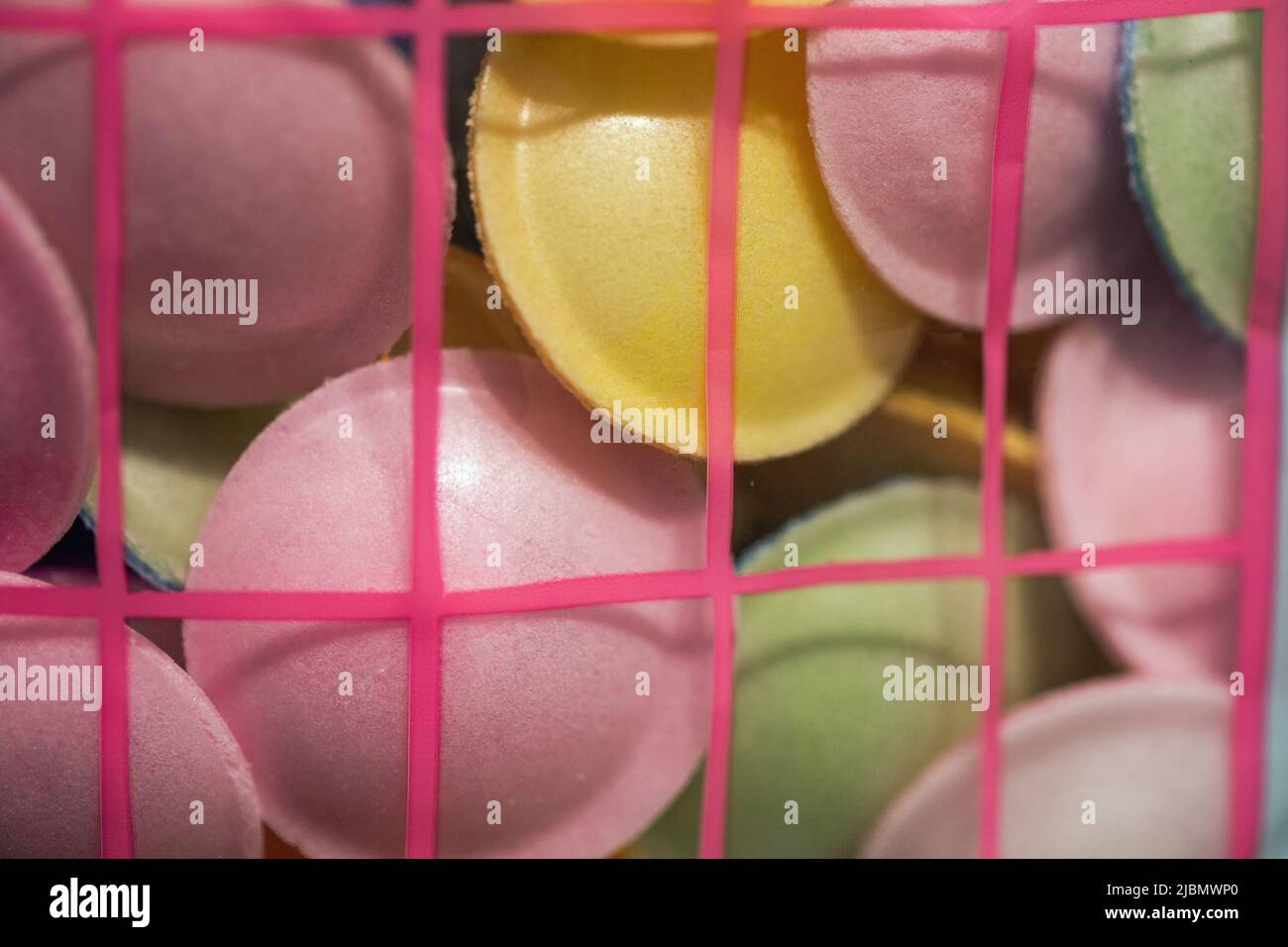 Circular puffed sweets in a range of colours held in a plastic basket and shot close up in landscape format Stock Photo
