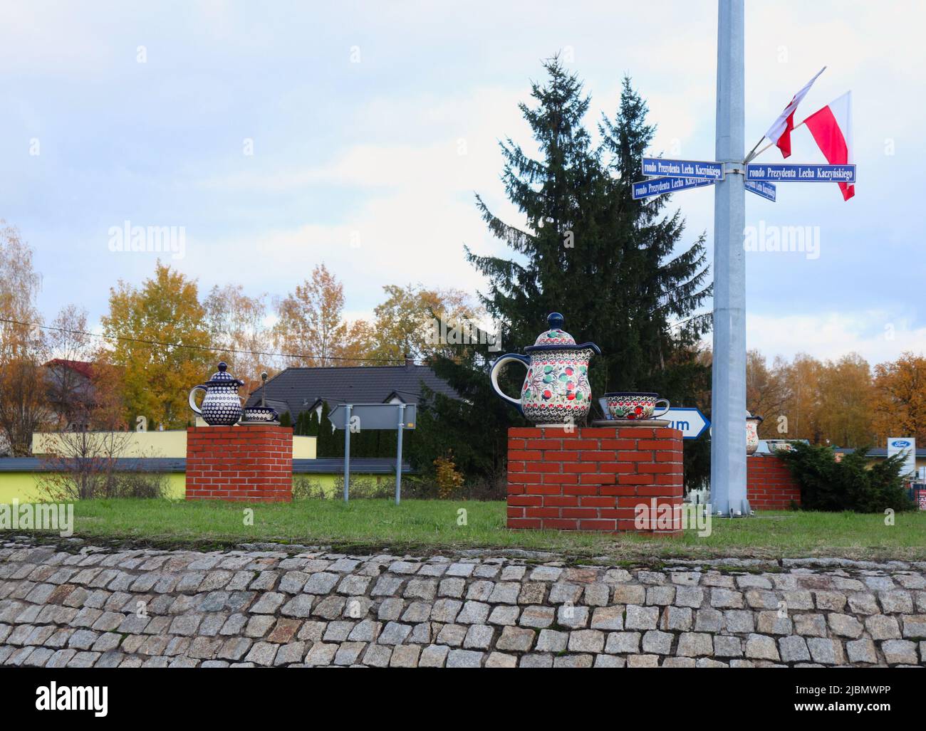 Flags on a pole with street signs above Polish pottery decorations in a roundabout in Boleslawiec, Poland on a fall day. Stock Photo