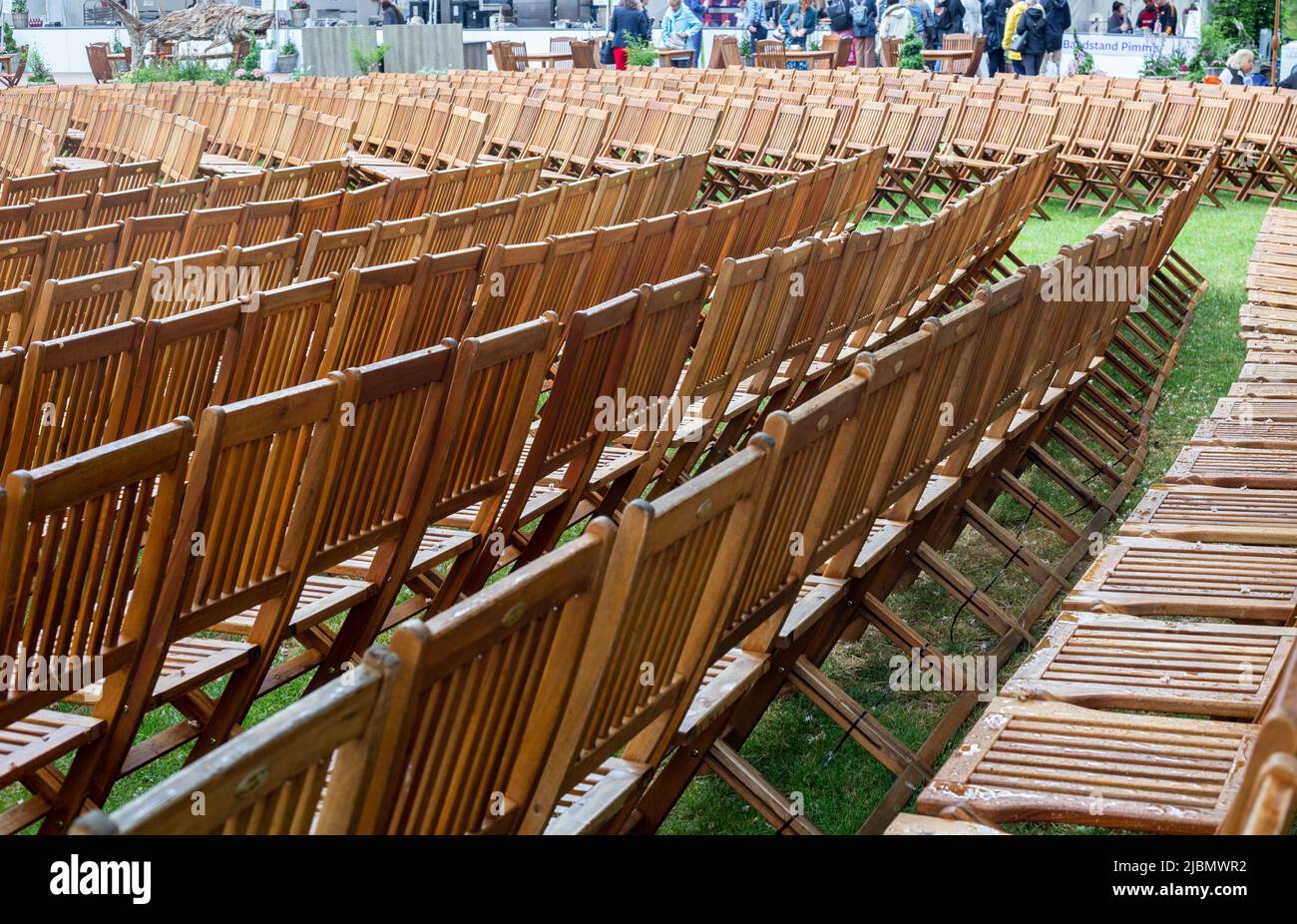 Chelsea, London, England, May 24th 2022, Many rows of wooden chairs with crowds seen in the background. Stock Photo