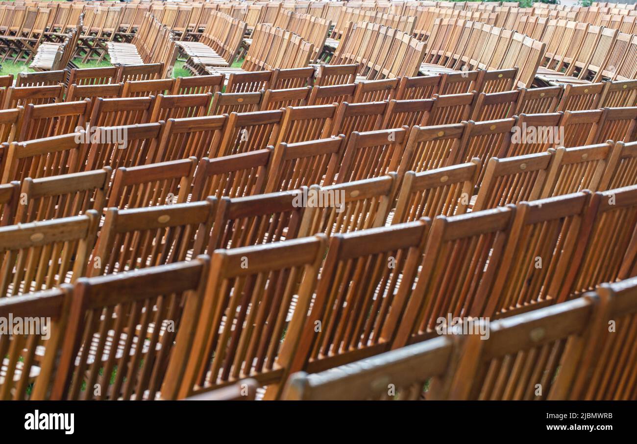 Rows of empty wooden chairs shot in landscape format with a telephoto lens Stock Photo