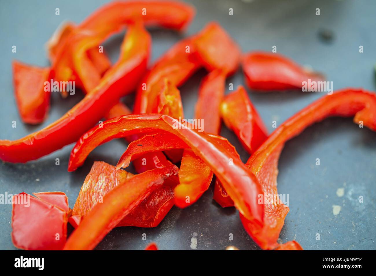 Chopped red peppers on a black coloured plancha shot close up in landscape format. Stock Photo
