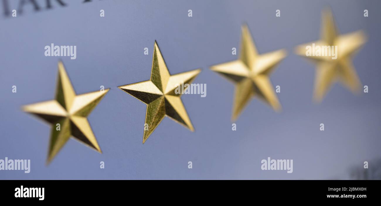 Four bevelled gold five pointed stars against a white background Stock Photo
