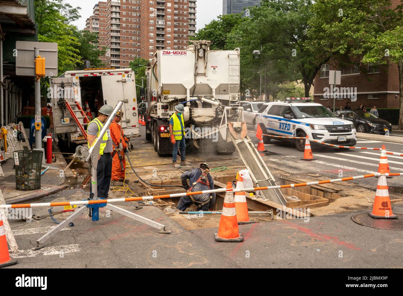 Workers pour cement into an excavation in the roadway after completing underground work on Ninth Avenue in Chelsea in New York on Saturday, May 28, 2022.(© Richard B. Levine) Stock Photo