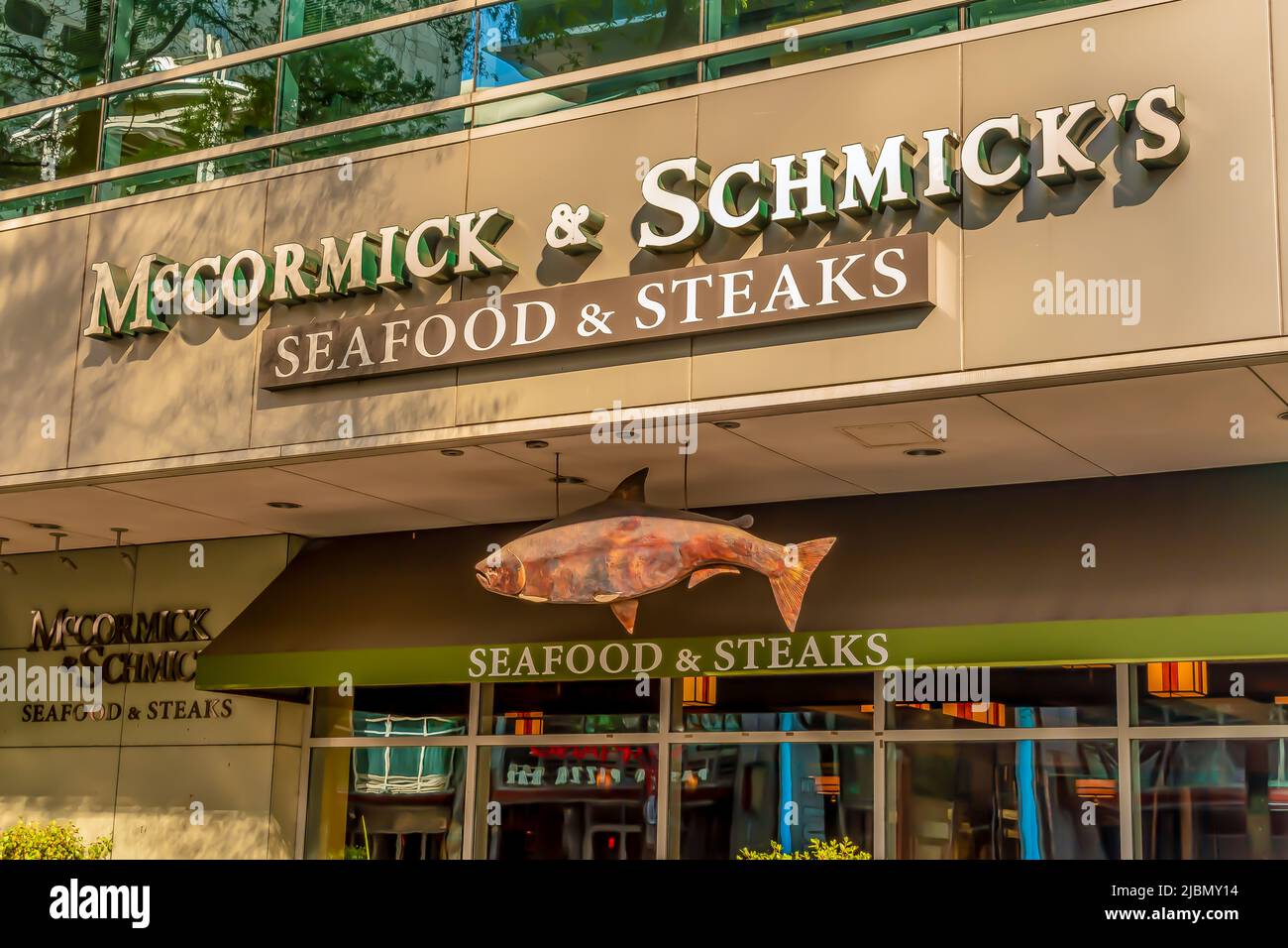 McCormick and Schmicks exterior facade brand and logo signage in light of dusk with hanging fish emblem and reflective glass in uptown Charlotte. Stock Photo