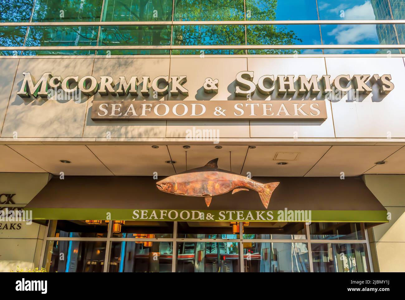McCormick and Schmicks exterior facade brand and logo signage in light of dusk with hanging fish emblem and reflective glass in uptown Charlotte. Stock Photo