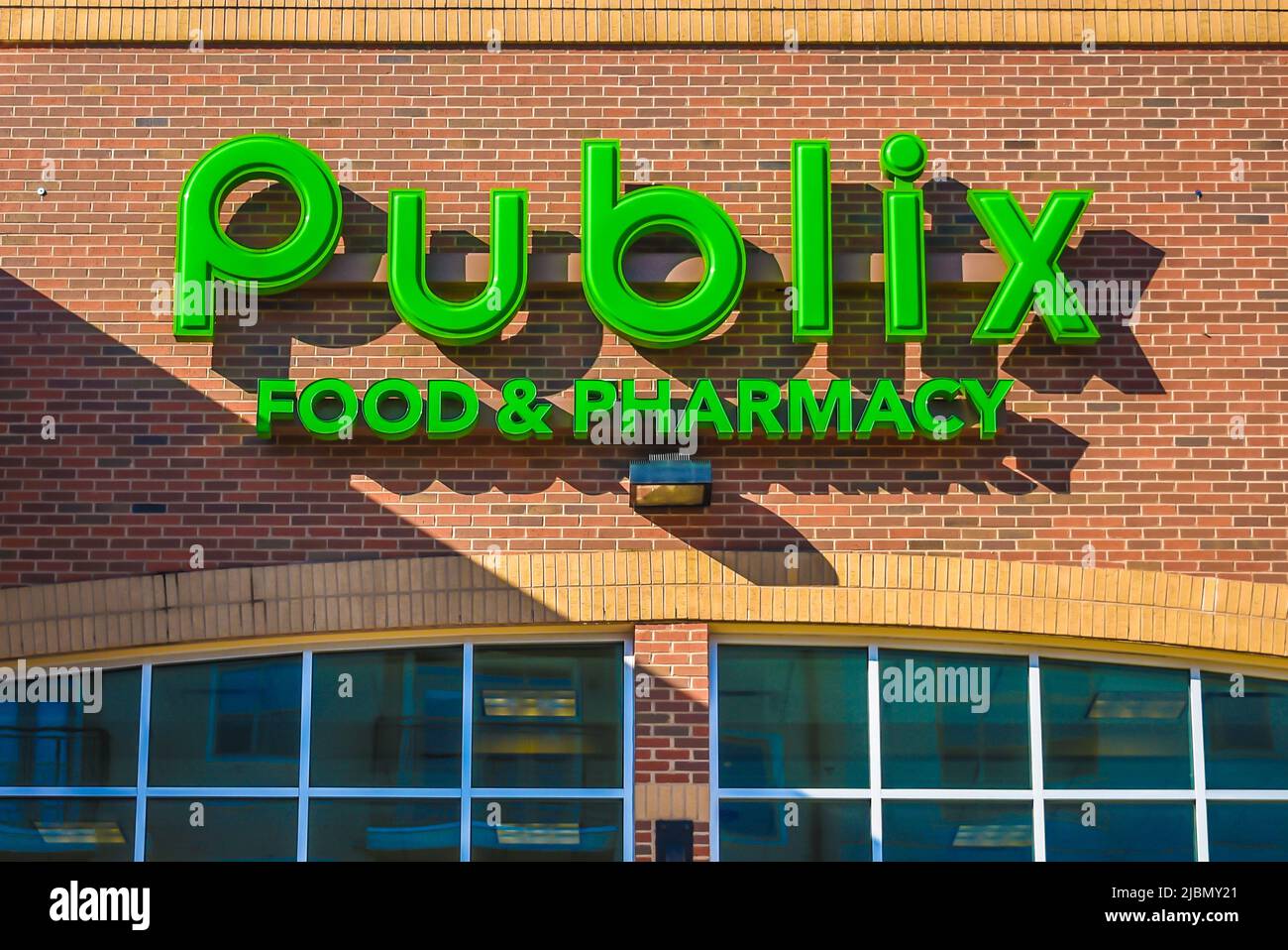 Publix Food and Pharmacy's exterior facade brand and logo signage in neon green with shadows at sunset on a sunny day in Charlotte, North Carolina. Stock Photo