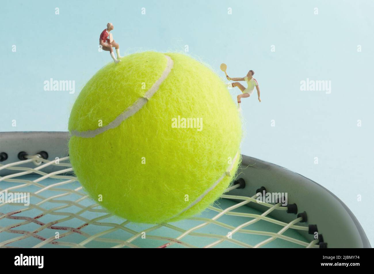 Miniature tennis players on tennis ball and racket playing match Stock Photo