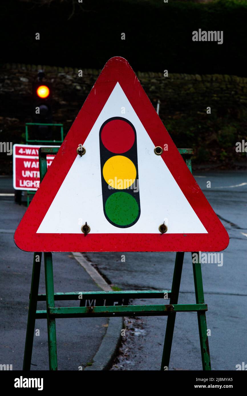 A temporary traffic light sign warning of roadworks ahead. There is 4 way traffic control at a junction of 4 roads in Baildon, Yorkshire. Stock Photo